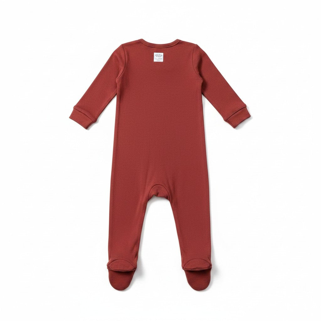 The RevenueCat Swag Store rust-red long-sleeve infant footed romper with a minimalist back view.